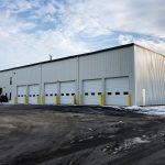 A large white building with yellow trim and six doors.